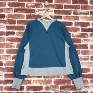 May include: A blue and beige sweatshirt with a contrasting colour block design. The sweatshirt has long sleeves and a crew neck.