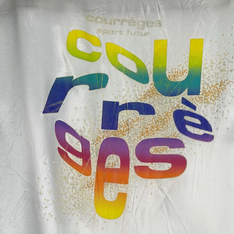 K&ouml;nnte beinhalten: Wei&szlig;es T-Shirt mit einer regenbogenfarbenen Grafik des Wortes "courr&egrave;ges" mit dem Text "sport futur" dar&uuml;ber.