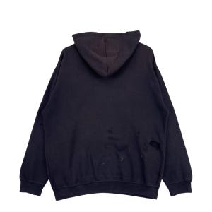 May include: A black hooded sweatshirt, seen from the rear. The garment shows signs of wear, with visible marks and small holes. The material looks to be soft and comfortable.