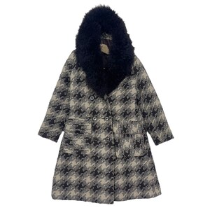 Puede incluir: Un abrigo largo de pata de gallo blanco y negro con un gran cuello de piel sintética negra.