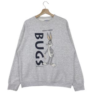 May include: A gray sweatshirt with a Bugs Bunny graphic and the text "NEW YORK" and "BUGS" printed on the front.