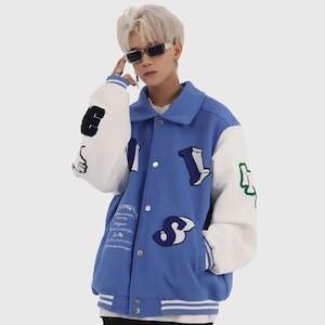 May include: A blue varsity jacket with white sleeves and colorful embroidered letters and graphics. The jacket has a button closure and a ribbed collar, cuffs, and hem.