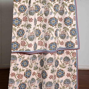 May include: A white cotton quilt with a floral pattern in shades of blue, green, and pink. The quilt has a blue and red border.