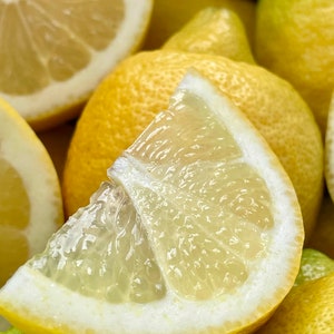 May include: A close-up of a pile of yellow lemons, some cut in half, showing the juicy flesh inside.