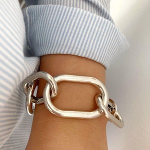 Peut inclure: Un bracelet en chaîne argent avec de gros maillons ovales.