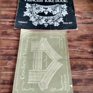 May include: Two vintage crochet pattern books. The top book, "Princess Yoke Book, Volume 1," is black with white text and a detailed lace design. The bottom book, "Crocheted Yokes," is light green with a lace yoke illustration.