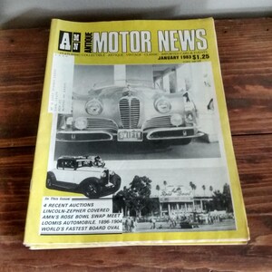 May include: A yellow magazine cover with the title "Antique Motor News" in black text. The cover features a black and white photo of a vintage car with the word "SWIFTY" on the license plate. The magazine is dated January 1983 and costs $1.25.