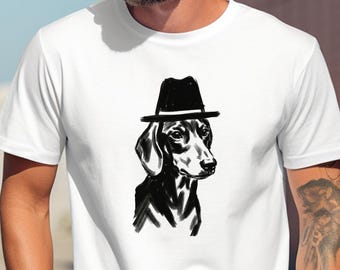 May include: White t-shirt with a black and white illustration of a dachshund wearing a black fedora. The word "white" is printed at the bottom of the shirt. A unique graphic design.