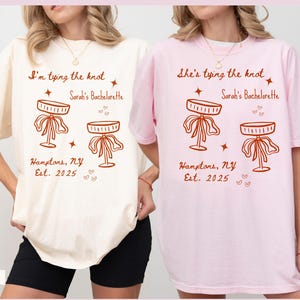 Comfort Colors® Personalized Coquette She&#39;s Tying the Knot Shirt, Custom Bow & Martini Bachelorette Party Favors, Destination Bach Tee Gift