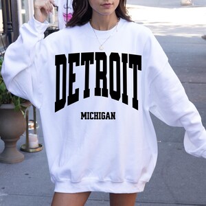 May include: White sweatshirt with black text that reads "DETROIT MICHIGAN".