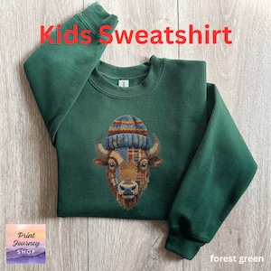 May include: Forest green kids' sweatshirt with the text "Kids Sweatshirt" in red. The sweatshirt features an embroidered bison wearing a plaid and striped beanie. The bison's face is a patchwork of plaid and brown.