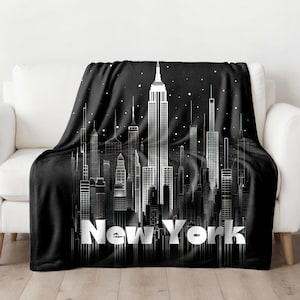 May include: Black fleece throw blanket with a white outline of the New York City skyline and the text "New York" in white.