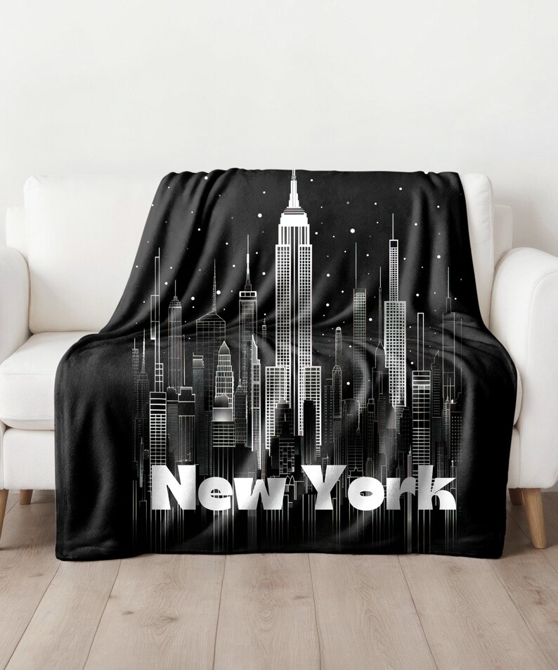 May include: Black fleece throw blanket with a white outline of the New York City skyline and the text "New York" in white.