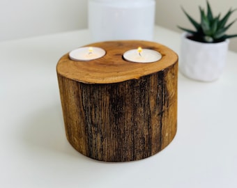 May include: A wooden candle holder with two tea lights, made from a tree trunk slice. The holder is dark brown with a natural wood grain pattern.