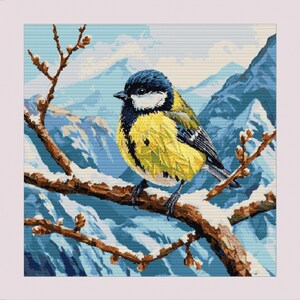 May include: A yellow and blue bird with a black head perched on a snow-covered branch in a wintery mountain landscape.