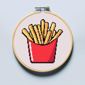 Könnte beinhalten: Ein Kreuzstich-Stickrahmen mit einem pixeligen Design von Pommes Frites in einer roten Tüte. Die Pommes sind gelb und goldfarben, mit schwarzer Umrandung. Der Rahmen ist aus Holz und hat einen Metallspannmechanismus.