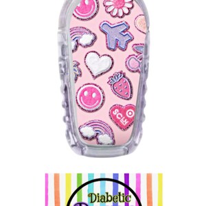 May include: A pink and white patterned sticker with a variety of cute designs, including hearts, rainbows, smiley faces, and a plane. The sticker is designed to fit a medical device and has the text "SCLM" on it. The sticker is from Diabetic Decor by Danica.