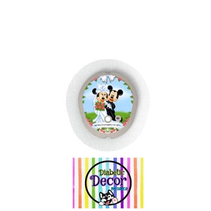May include: A round, white, adhesive patch with a colorful design featuring Mickey and Minnie Mouse dressed in wedding attire. The text "And they lived happily ever after..." is printed below the characters. The patch is for a diabetic glucose monitor.