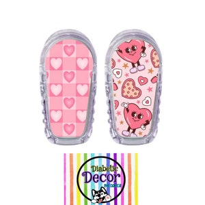 May include: Two clear medical device covers with pink heart designs. One features a pink and white checkered pattern with hearts, the other has a cartoon heart character with stars and heart-shaped cookies. The logo "Diabetic Decor by Domica" is at the bottom.