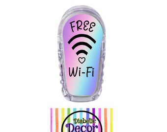 May include: A clear plastic sticker with a rainbow gradient background. The sticker has a black wifi symbol and the words "FREE Wi-Fi" in black text. The sticker is designed to be placed on a medical device. The sticker is from Diabetic Decor by Dominica.