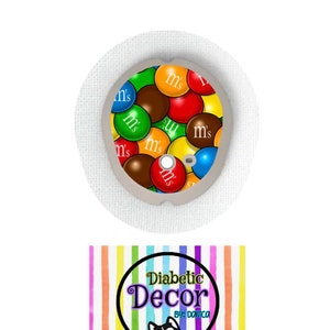 May include: A white round medical patch with a colorful M&M's design. The patch has a small round hole in the center. Below the patch is a colorful striped background with a circle containing the text "Diabetic Decor by: Danica" and a cartoon husky dog.