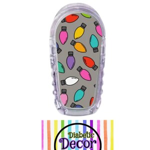 May include: A gray background with a pattern of colorful light bulbs. The light bulbs are in various shades of pink, red, yellow, green, blue, and purple. The pattern is on a clear plastic cover for a medical device. The text "Diabetic Decor by Domica" is on a rainbow striped background.