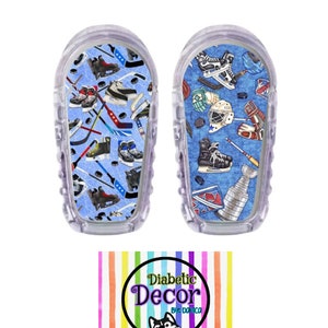 May include: Two clear plastic medical device covers with a hockey themed design. The design features hockey sticks, pucks, skates, and a hockey helmet on a blue background with white lines. The text "Diabetic Decor by Danica" is on a rainbow striped background.