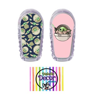 May include: Two clear plastic medical device covers with colorful adhesive stickers. One sticker features a repeating pattern of a green cartoon character with big eyes. The other sticker features a single green cartoon character holding a lightsaber. The stickers are labeled "Diabetic Decor by Dominica".