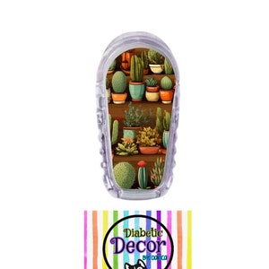 May include: A clear plastic medical device with a colorful sticker featuring a pattern of potted cacti and succulents. The sticker has the text "Diabetic Decor by Danica".