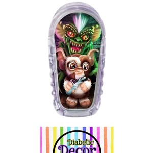 May include: A clear plastic insulin pump cover with a colorful graphic of the characters Gizmo and Stripe from the movie Gremlins. The cover is decorated with a brick wall background. The text "Diabetic Decor by Danica" is printed on a rainbow striped background.