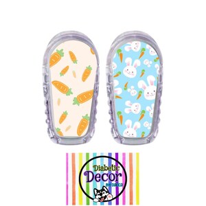 May include: Two clear plastic medical device covers with colorful patterned stickers. One sticker features a light blue background with white bunnies and orange carrots. The other sticker features a light yellow background with orange carrots. The stickers have the text "Diabetic Decor by Domico" printed on them.