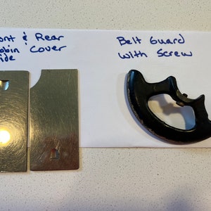 May include: Two silver metal plates with a small hole in each, labeled "Front & Rear Bobbin Cover Slide". A black plastic belt guard with a screw, labeled "Belt Guard with Screw".