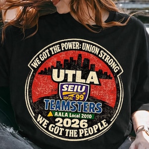 May include: Black t-shirt with a circular graphic featuring the text "UTLA SEIU Local 99 TEAMSTERS AALA Local 2010 2026" and the phrases "WE GOT THE POWER: UNION STRONG" and "WE GOT THE PEOPLE".