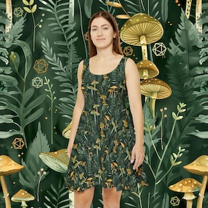 Puede incluir: Una mujer lleva un vestido verde con estampado de setas y follaje. El vestido tiene un corpiño ajustado y una falda acampanada. El estampado es de color verde oscuro y dorado.