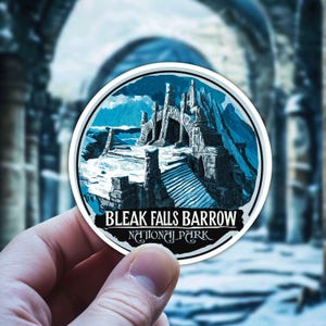 May include: A round sticker featuring a blue and white illustration of a stone archway and a snowy landscape. The text "BLEAK FALLS BARROW NATIONAL PARK" is printed in black at the bottom of the sticker.