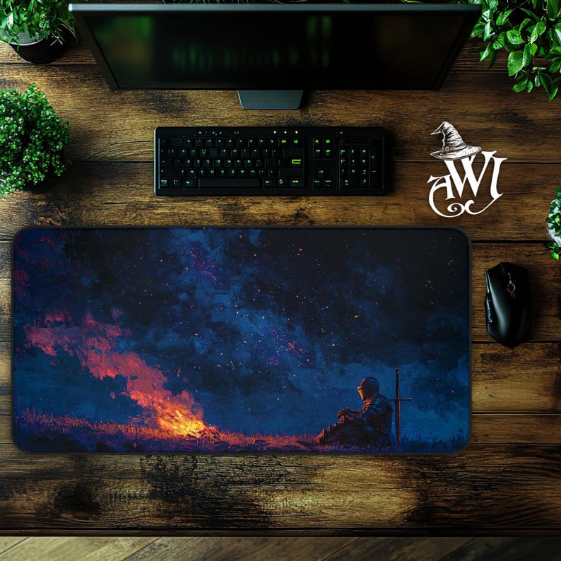 May include: A rectangular mouse pad featuring a digital painting of a knight sitting near a campfire under a starry sky. The color palette includes shades of blue, orange, and black. A keyboard, mouse, and monitor are visible.