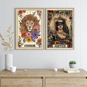 K&ouml;nnte beinhalten: Zwei Tarotkarten mit floralen R&auml;ndern. Die erste Karte ist die Karte der Courage und zeigt einen L&ouml;wen mit einer Krone. Die zweite Karte ist die Karte der Gerechtigkeit und zeigt eine Frau mit verbundenen Augen, die eine Waage h&auml;lt.