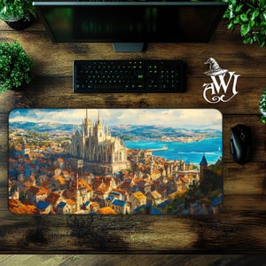 May include: A rectangular mouse pad featuring a detailed painting of a European city with a large cathedral, blue water, and mountains in the background. The mouse pad has a black border and is on a wooden desk.