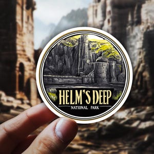 May include: A round sticker featuring a detailed illustration of Helm's Deep, a fortress from a fantasy setting. The design includes a stone castle, mountains, and the text "HELM'S DEEP - NATIONAL PARK" in a stylized font, with a black and gold border.