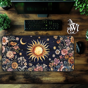 May include: A dark blue mousepad with a floral design featuring a large sun and moon with stars. The sun is yellow and gold with a white center. The moon is white with a crescent shape. The flowers are in shades of pink, purple, yellow, and white.