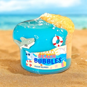 May include: A blue and yellow slime jar with a shark, a life preserver, and the text "Shark Beach Bubbles Fuzzy Slimes".