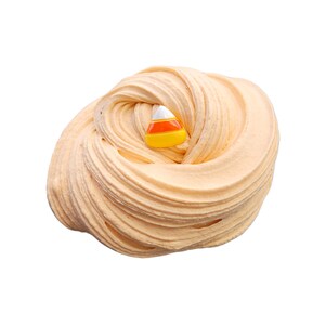 May include: A swirl of light orange slime with a candy corn charm. The slime has a smooth, textured appearance, and the candy corn charm is white, orange, and yellow. This is a fun, sensory toy for kids.