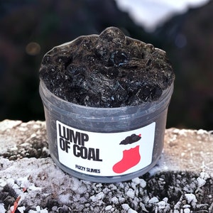 May include: A black slime in a clear plastic container with a white label that says "Lump of Coal Fuzzy Slimes". The label also has a red stocking with a black cloud on top.