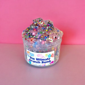 May include: A clear plastic jar filled with a sparkly, colorful slime with the label "The Ultimate Crunch Bomb" and "Fuzzy Slimes" printed on it.