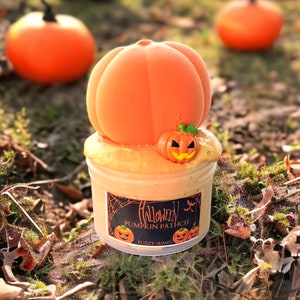 May include: Orange pumpkin-shaped slime with a small pumpkin charm on top. The slime is in a clear jar with a black label that says "Halloween Pumpkin Patch" and "Fuzzy Slimes".
