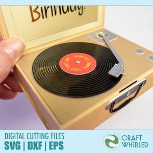 Puede incluir: Una tarjeta dorada con forma de tocadiscos en miniatura con un disco de vinilo negro. El disco tiene una etiqueta roja con el texto "SOME OLD THINGS STILL COOL". La tarjeta est&aacute; abierta, revelando la palabra "Birthday". Una mano sostiene la tarjeta.