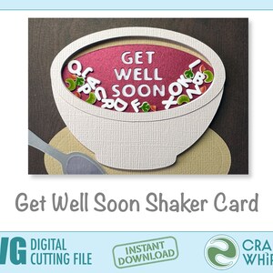 Op de afbeelding: Een witte kom met een rode binnenkant en een lepel, gevuld met kleurrijke letters die "Get Well Soon" spellen. De kom staat op een bruine achtergrond met een beige mat eronder. De tekst "Get Well Soon Shaker Card" staat onder de kom.