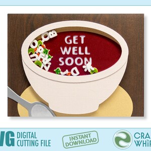 Op de afbeelding: Een witte kom met rode soep met de woorden "Get Well Soon" in de soep. De kom staat op een bruine houten achtergrond met een zilveren lepel.