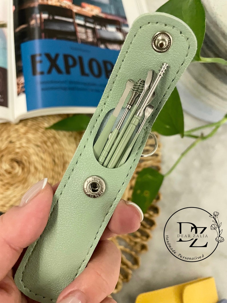 May include: A sage green leather case with a snap closure, containing a set of six silver tools. The case has the text "Dear Zalia Handmade Personalised" on the bottom.