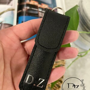 May include: Black leather keychain with a silver metal ring and the initials "D.Z." engraved in silver. The keychain is handmade and personalized.